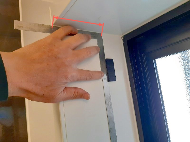 簡易内窓の取り付けを容易にするための、位置決めガイドを窓枠に貼り付けるところ。